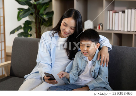 Family Bonding. Mother and son enjoying screen time together with smartphone. 129398466