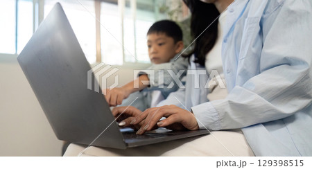 Learning Together. Mother and son collaborating on a laptop. 129398515