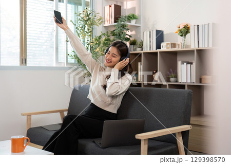 Joyful Music Experience. Woman dancing with phone at home. 129398570