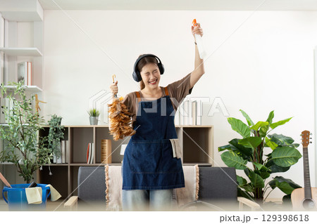 Home Cleaning. Excited woman celebrating while cleaning, showcasing joy in household tasks. Home Cleaning. Excited woman celebrating while cleaning, showcasing joy in household tasks. 129398618