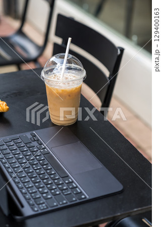 Take away coffee in a plastic cup and fresh croissant, working at cafe Take away coffee in a plastic cup and fresh croissant, working at cafe 129400163