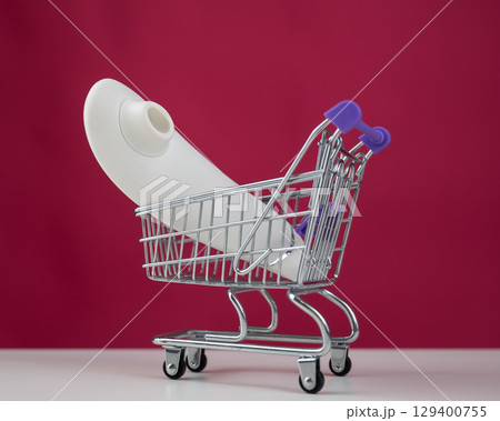 Clitoral vibrator in miniature shopping cart on pink background.  129400755