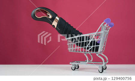 Sex toy in miniature shopping cart on pink background.  129400756