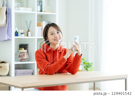 リビングでスマホを使う若い女性 129401542