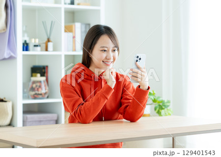 リビングでスマホを使う若い女性 129401543