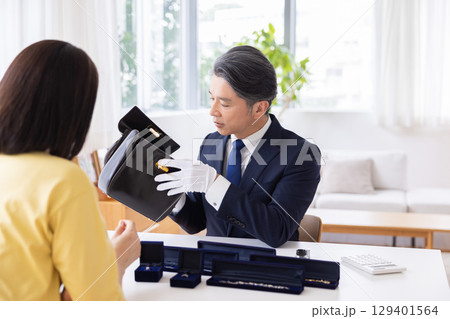 出張買取　査定　訪問先で鑑定をしている男性 129401564