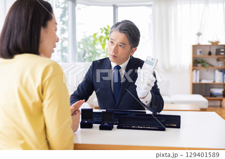 出張買取　査定　訪問先で鑑定をしている男性 129401589