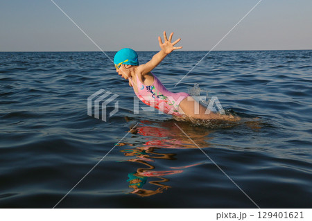 Girl swimmer 8 years old jumps out of sea and swimming in sunny day 129401621