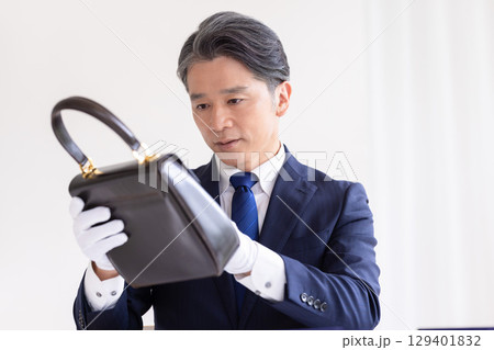 出張買取　バックの査定をしている男性 129401832