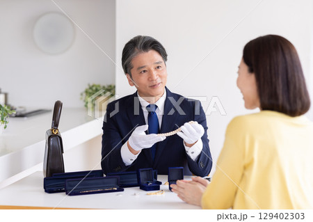 出張買取　査定　訪問先で鑑定をしている男性 129402303