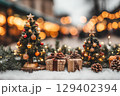 Cozy Christmas Decor with Miniature Trees and Gift Boxes Against a Winter Wonderland Background 129402394