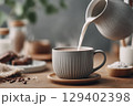Pouring Milk into a Coffee Cup with Warm Background and Natural Ingredients 129402398