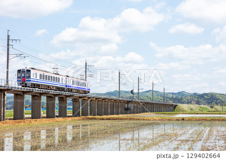 【ほくほく線】水田広がる高架を走行する普通列車 129402664