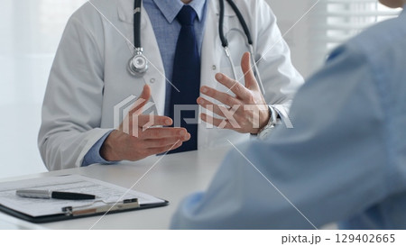 Medical professional explaining diagnosis, gesturing hands to patient during consultation in well lit clinical setting. Medicine and health care concept Medical professional explaining diagnosis, gesturing hands to patient during consultation in well lit clinical setting. Medicine and health care concept 129402665