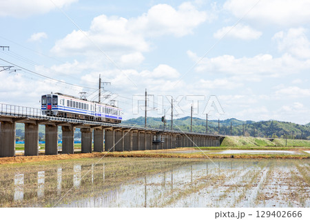 【ほくほく線】水田広がる高架を走行する普通列車 129402666