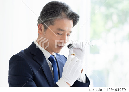 出張買取　貴金属の査定をしている男性 129403079