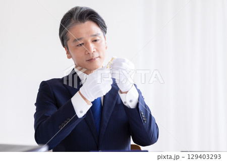 出張買取　貴金属の査定をしている男性 129403293