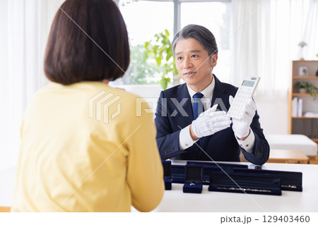 出張買取　査定　訪問先で鑑定をしている男性 129403460