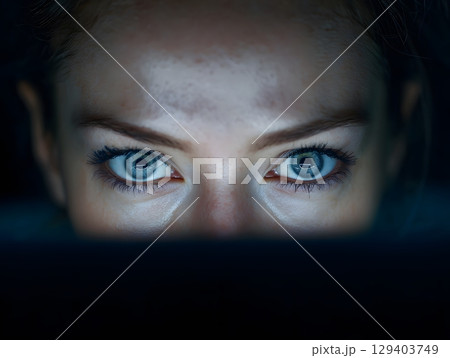 photo of empty eyes staring at computer screen in darkness, 129403749