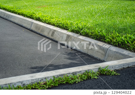 縁石に沿って生い茂る青々とした草と道路 129404022