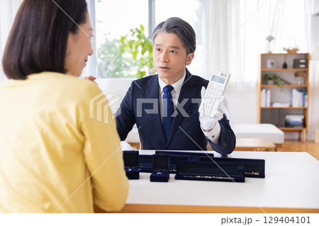 出張買取　査定　訪問先で鑑定をしている男性 129404101
