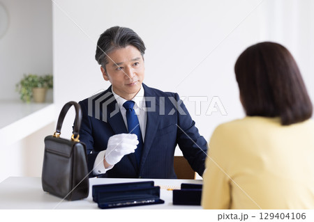 出張買取　査定　訪問先で鑑定をしている男性 129404106