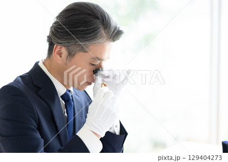 出張買取　貴金属の査定をしている男性 129404273