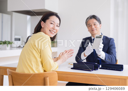出張買取　自宅で査定をしてもらっている主婦 129406089