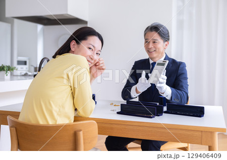 出張買取　自宅で査定をしてもらっている主婦 129406409