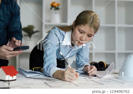 Engineer and architect collaborate on blueprint designs in modern office environment focused on innovative concepts 129406702