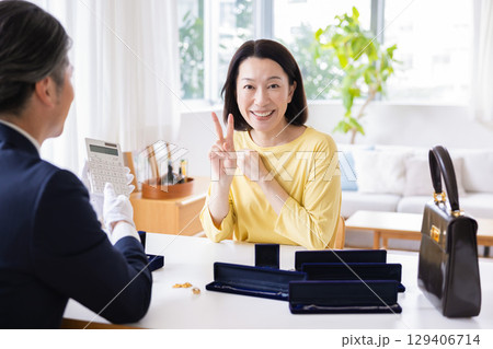 出張買取　自宅で査定をしてもらっている主婦 129406714