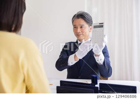 出張買取　査定　訪問先で鑑定をしている男性 129406886