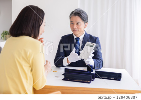 出張買取　査定　訪問先で鑑定をしている男性 129406887