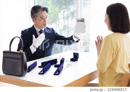 出張買取　査定　訪問先で鑑定をしている男性 129406917