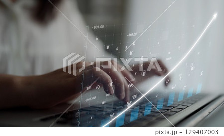 Hands Typing on Laptop with Financial Graph and Currency Symbols Overlay in Modern Office Environment Depicting Digital Growth and Investment Strategies Copula 129407003