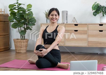 Young Woman Practicing Yoga at Home for Wellness and Relaxation in a Modern Living Room Setting Young Woman Practicing Yoga at Home for Wellness and Relaxation in a Modern Living Room Setting 129407488