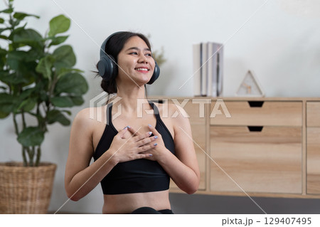 Young Woman Practicing Mindfulness and Relaxation at Home with Headphones for a Holistic Wellness Experience Young Woman Practicing Mindfulness and Relaxation at Home with Headphones for a Holistic Wellness Experience 129407495