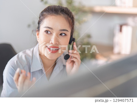 Professional Interaction. Engaged woman on headset discussing with clients in a bright office. 129407571