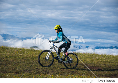 Asian woman riding mountain bike on beautiful mountain top Asian woman riding mountain bike on beautiful mountain top 129410050
