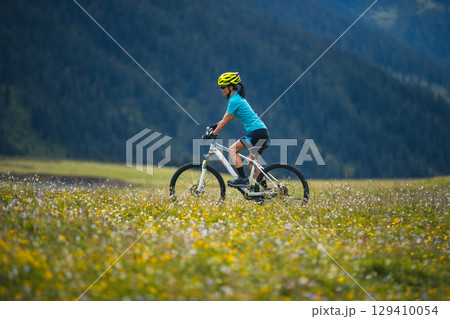 Woman cyclist riding mountain bike on beautiful mountain top Woman cyclist riding mountain bike on beautiful mountain top 129410054