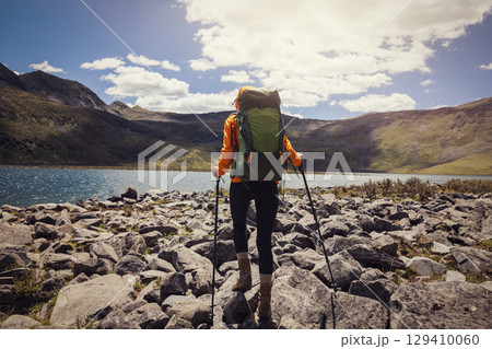 Woman hiking on high altitude mountains, walking to a beautiful lake 129410060