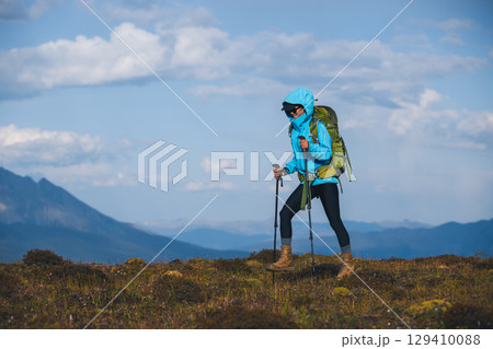 Backpacking woman hiking on sunset high altitude mountain top 129410088