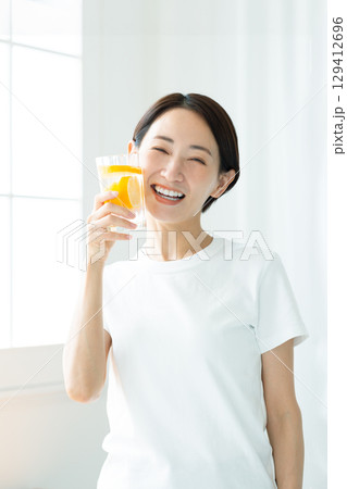 レモン水のグラスを持つ透明感のある笑顔の若い女性 上半身 レモン水のグラスを持つ透明感のある笑顔の若い女性 上半身 129412696