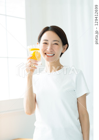 レモン水のグラスを持つ透明感のある笑顔の若い女性 上半身 レモン水のグラスを持つ透明感のある笑顔の若い女性 上半身 129412699