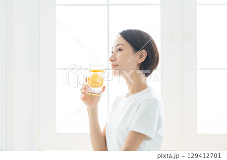 レモン水のグラスを持つ透明感のある若い女性 上半身 129412701