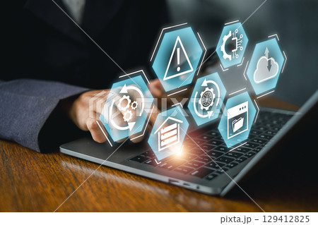 Businessperson using laptop with digital icons representing disaster recovery and data protection. 129412825