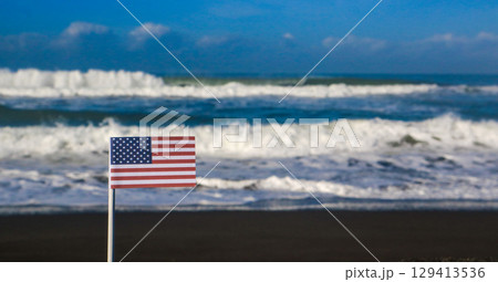 American national flag on a sandy beach with the sea in the background. Travel destination and Independence day concept  129413536