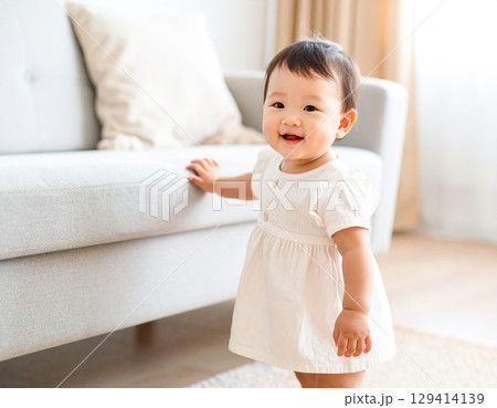 ソファーにつかまり立ちしている女の子 129414139