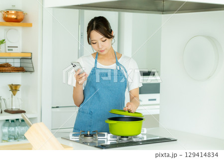 キッチンに立つ笑顔の若い女性 キッチンに立つ笑顔の若い女性 129414834