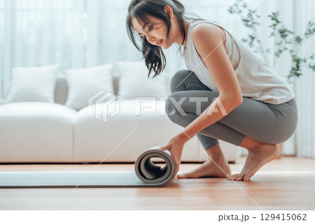 Young Asian woman doing yoga, twisting on a mat in the living room at home 129415062